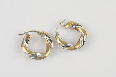 Lot 1430 - A pair of white and yellow metal hoop earrings,...