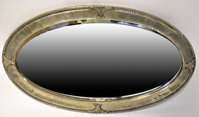 Lot 58 - An oval wall mirror with hammered metal frame,...