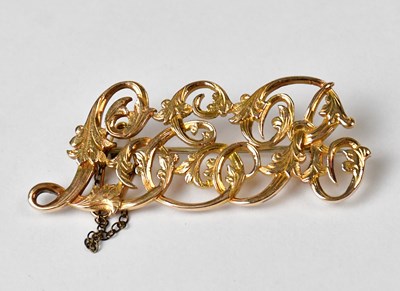 Lot 885 - A yellow metal brooch in the form of scrolling...
