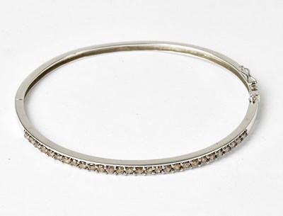 Lot 852 - A 14ct white gold bangle with a row of...