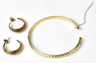 Lot 864 - A 9ct gold bangle with engraved decoration,...