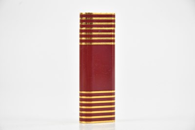 Lot 1435 - CARTIER; a red enamel and gold plated lighter,...