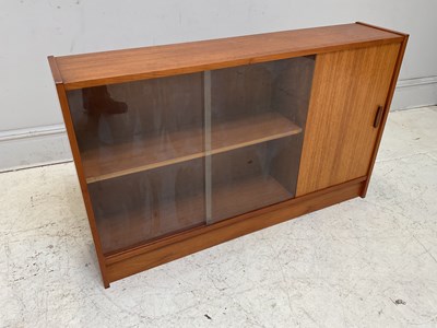 Lot 1185 - A mid century teak bookcase with sliding...