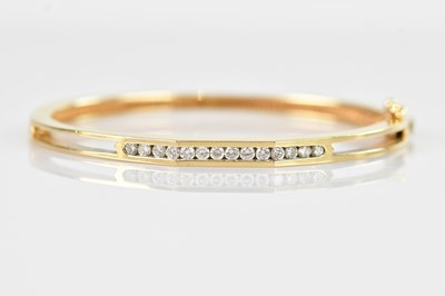 Lot 80 - A yellow metal diamond set hinged snap bangle,...