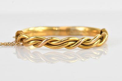 Lot 105 - A yellow metal hinged snap bangle with twisted...