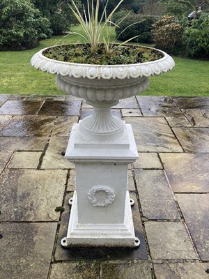 Lot 1221 - A cast iron garden urn on integral plinth,...