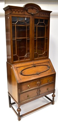 Lot 58 - A 1930s Jacobethan carved oak bureau bookcase...