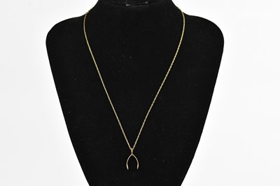 Lot 397 - A 9ct yellow gold wishbone pendant, suspended...
