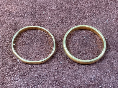 Lot 590 - A 22ct gold band ring and another similar,...