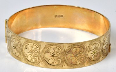 Lot 802 - A 9ct yellow gold hinged bangle, with foliate...