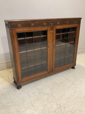 Lot 1145 - A 1930s oak bookcase with two glazed doors,...