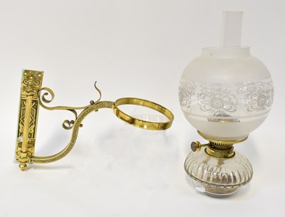 Lot 86 - A wall-mounted glass and brass oil lamp, the...