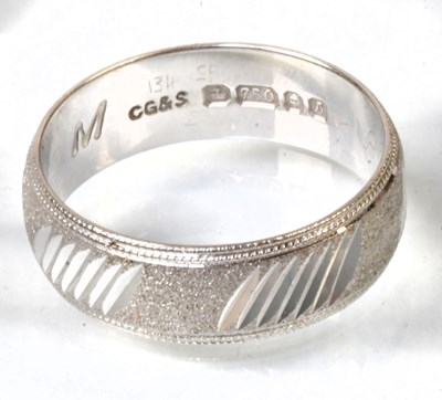 Lot 773 - An 18ct white gold textured wedding band with...
