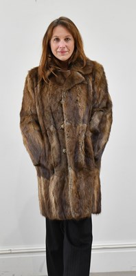 Lot 1379 - A knee-length light brown musquash coat with...
