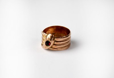 Lot 952 - A 9ct rose gold snake ring with ruby-coloured...