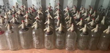 Lot 76 - Sixty glass soda syphons with plastic tops,...