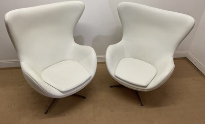 Lot 632 - A pair of modern white faux leather egg chairs...