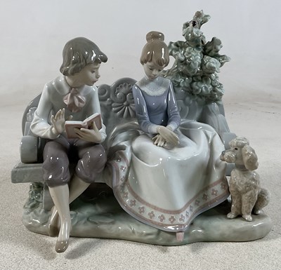 Lot 189 - LLADRO; a figure group of a seated boy reading...