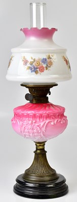 Lot 85 - A vintage brass oil lamp with pink glass well...