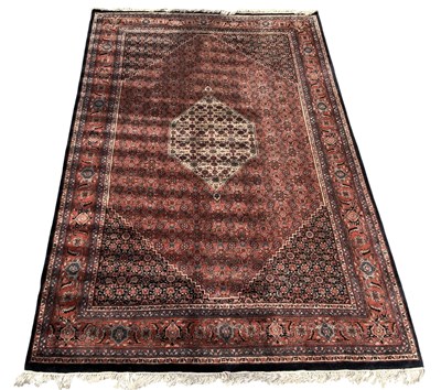 Lot 104 - A machine made Persian style red ground carpet,...