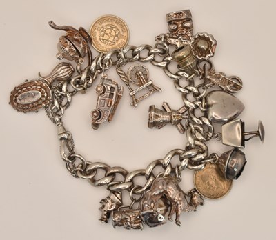 Lot 1553 - A silver charm bracelet with nineteen charms...