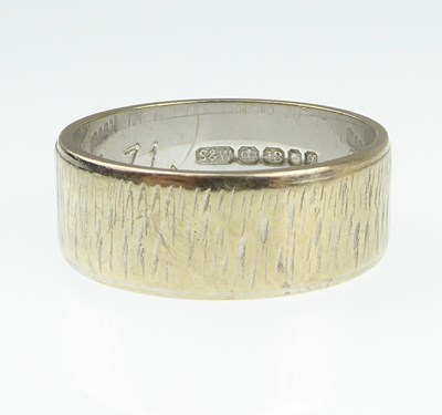 Lot 929 - An 18ct gold wedding ring with textured finish,...