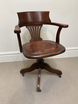 Lot 1043 - An early 20th century oak revolving desk chair,...