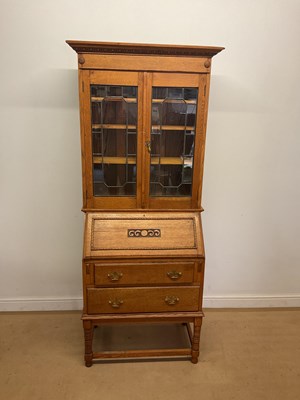 Lot 780 - A light oak bureau cabinet, with carved panel...