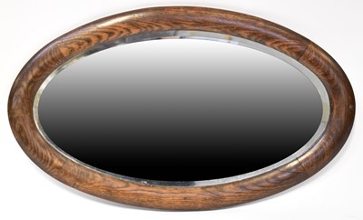 Lot 105 - An oak framed oval wall mirror with bevelled...