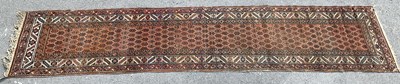 Lot 1398 - A decorative Afgan runner on a red ground, 300...