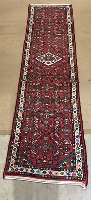 Lot 809 - A hand woven Persian style runner deep red in...