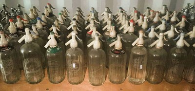 Lot 83 - Sixty glass soda syphons with plastic tops,...