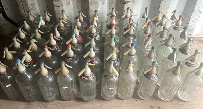 Lot 56 - Sixty glass soda syphons with plastic tops,...
