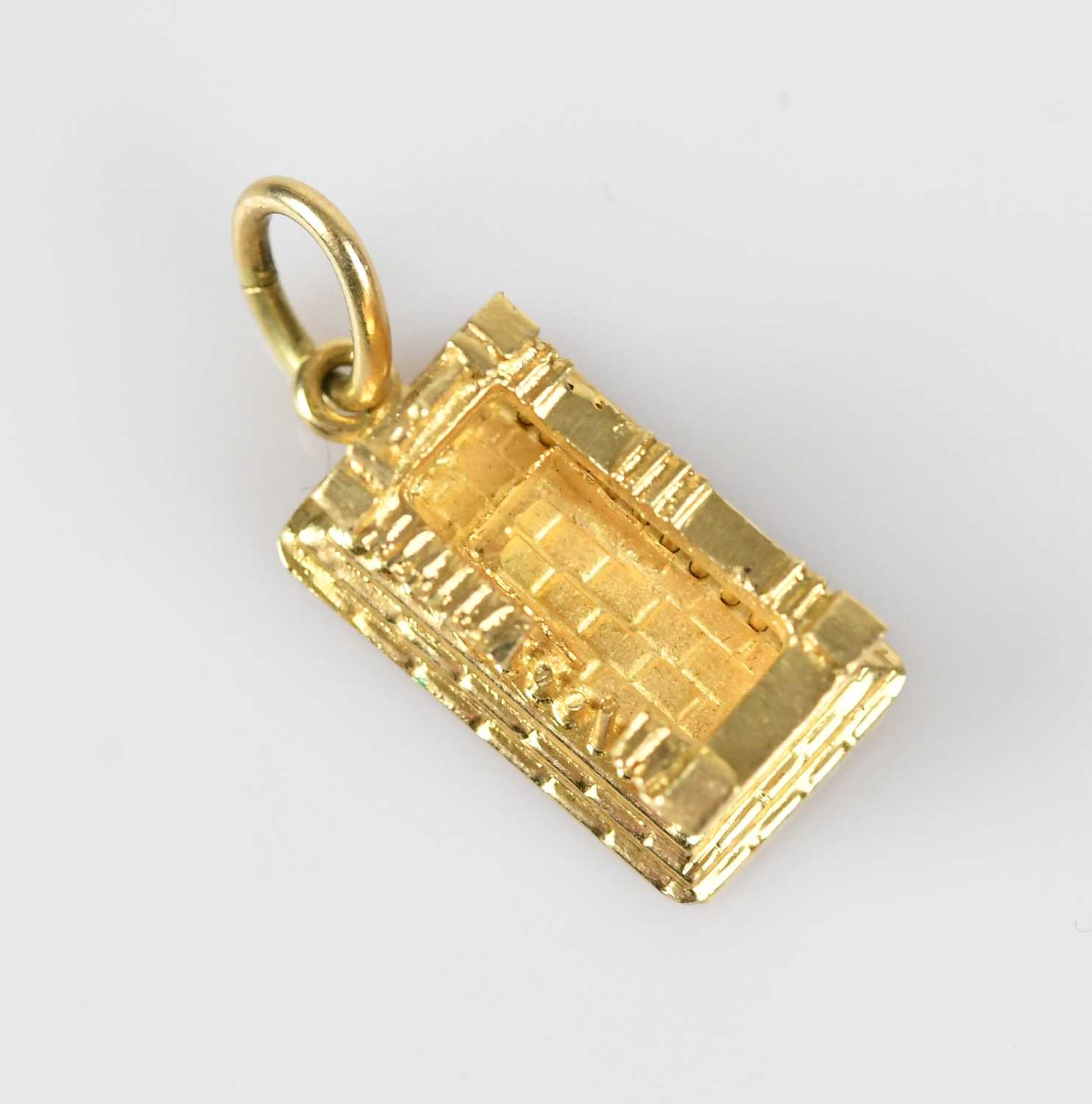 Lot 29 - A yellow metal charm of classical ruins,...