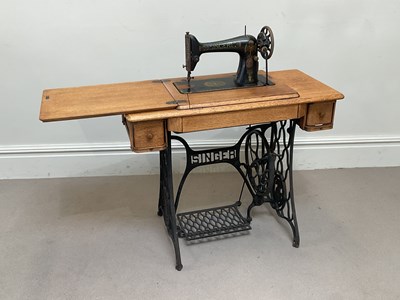 Lot 2011 - SINGER; an oak and iron treadle sewing machine,...