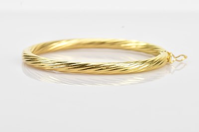 Lot 106 - A heavy gauge yellow metal hinged snap bangle...