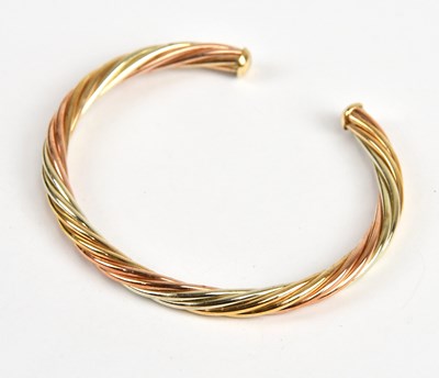 Lot 54 - A 9ct tricolour gold twist effect bangle,...