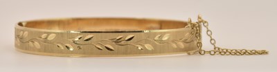 Lot 1494 - A 9ct gold hinged bangle with chased floral...
