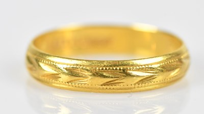 Lot 533 - A 22ct yellow gold wedding band with textured...