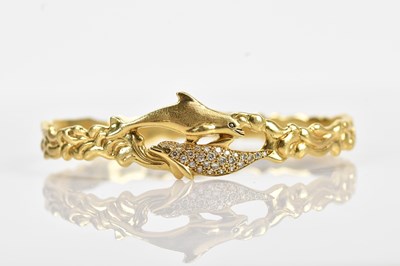 Lot 111 - A yellow metal diamond set dolphin wave bangle,...