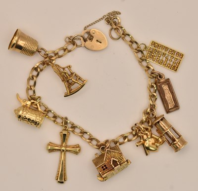 Lot 1409 - A 9ct yellow gold charm bracelet, with nine...