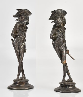 Lot 614 - A pair of silvered metal figural candlesticks,...