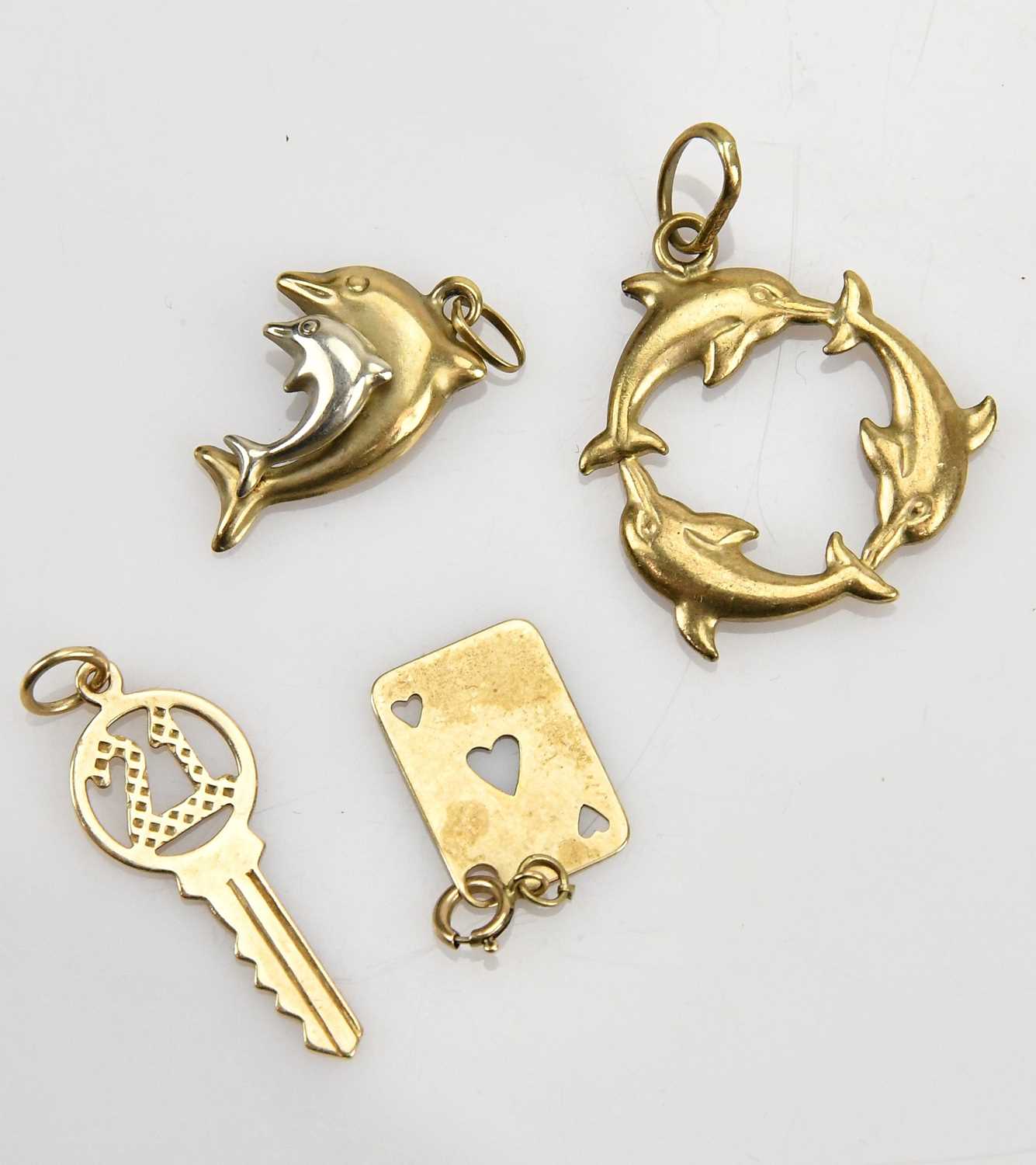 Lot 23 - A collection of four yellow metal charms,...