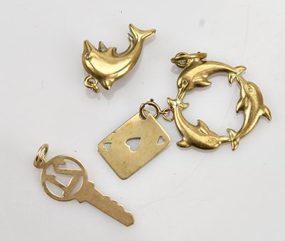 Lot 23 - A collection of four yellow metal charms,...