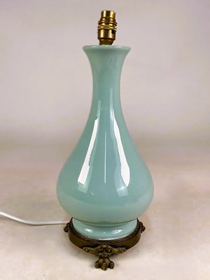 Lot 633 - A celadon glass table lamp on a circular brass...