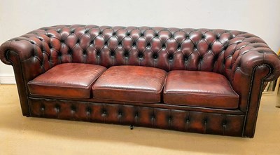 Lot 650 - A red Chesterfield leather three seat sofa,...