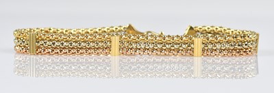 Lot 86 - A tricoloured textured bracelet stamped '750',...