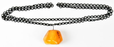 Lot 600 - A c.1960s amber pendant on a continuous black...