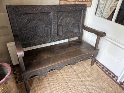 Lot 1058 - A carved oak settle, 18th century and later...