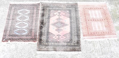 Lot 110 - Three rugs of pink ground, one being a Bokhara...